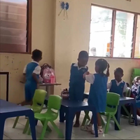 Kleine meid helpt klasgenootje zonder armen met eten