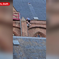 Man klimt op dak Oude Kerk in Delft